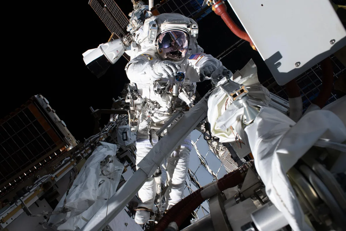 Imagem ilustrativa de uma caminhada espacial na ISS com astronauts trabalhando na instalação de células solares.