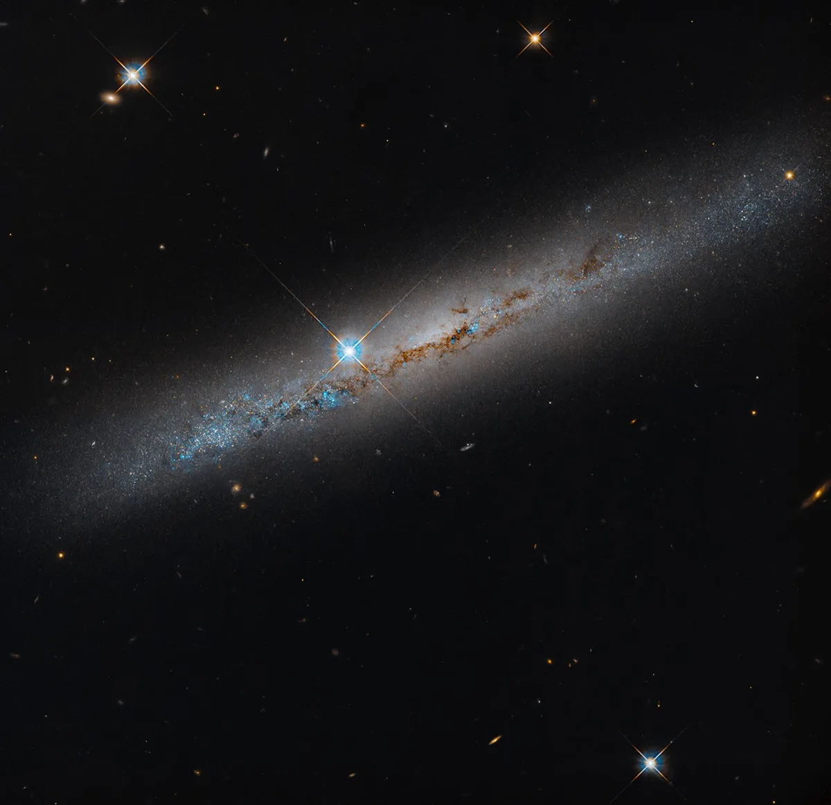Foto da galáxia NGC 1827 mostrada pelo telescópio Hubble, com detalhes de estrelas e poeira intergaláctica.