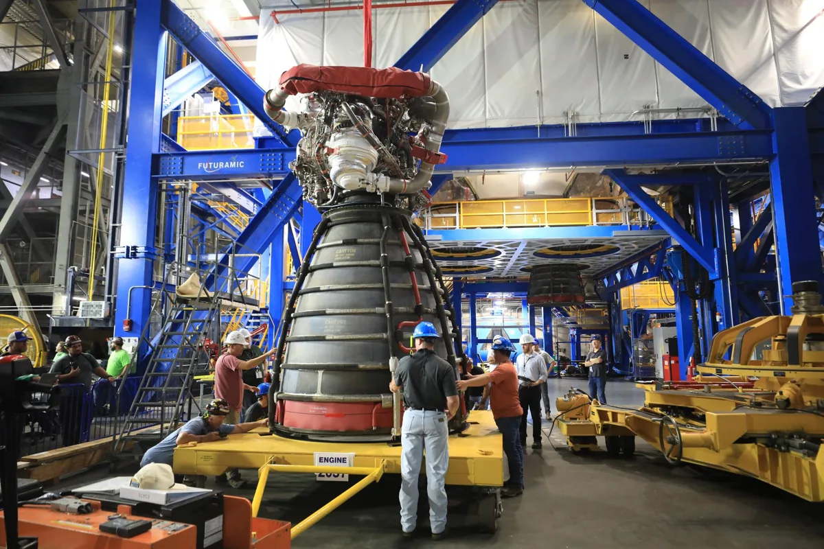 Técnicos ajustando motores RS-25 no foguete SLS na plataforma de lançamento da NASA.