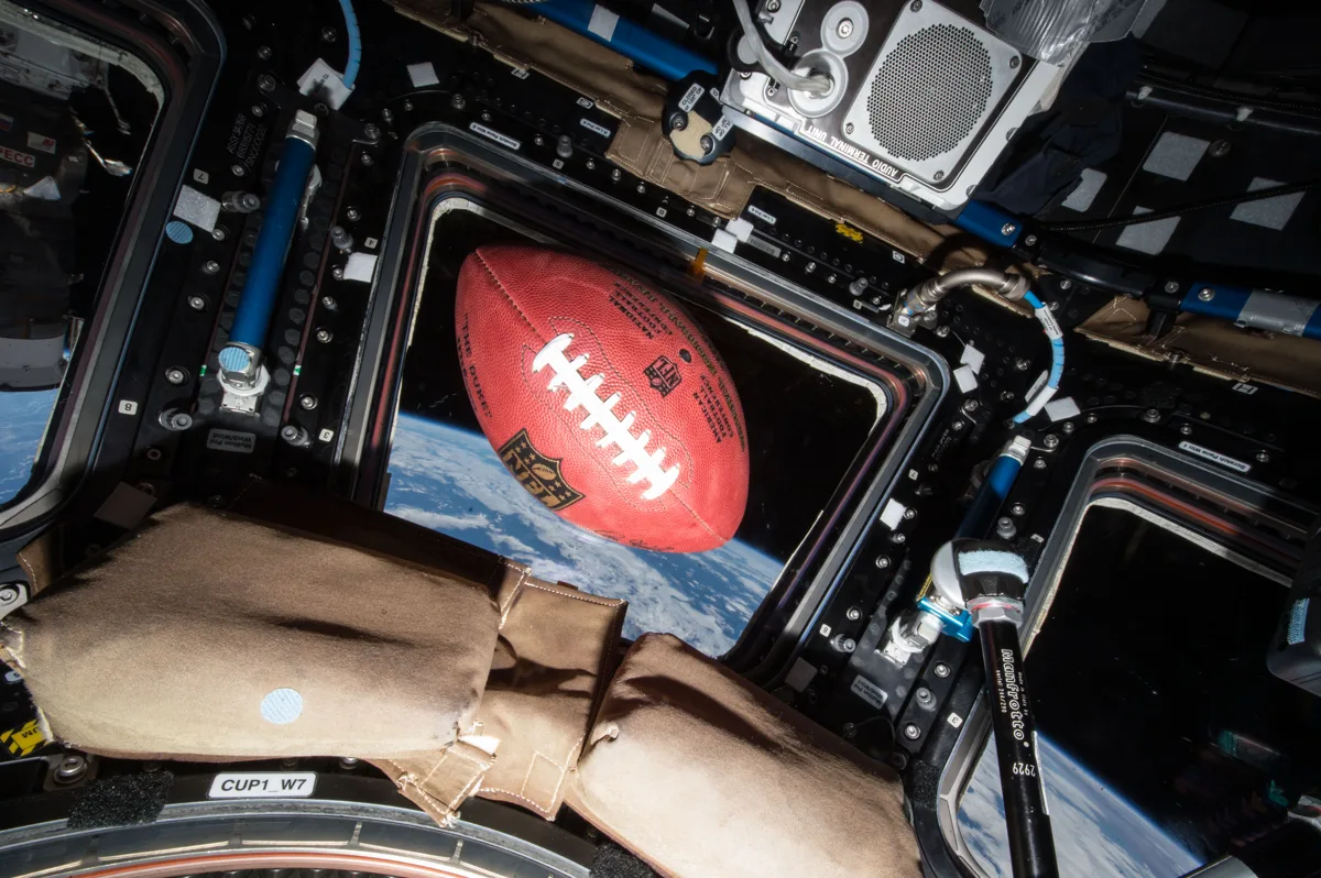 Imagem de um avião da NASA sobrevoando estádio de futebol americano durante evento