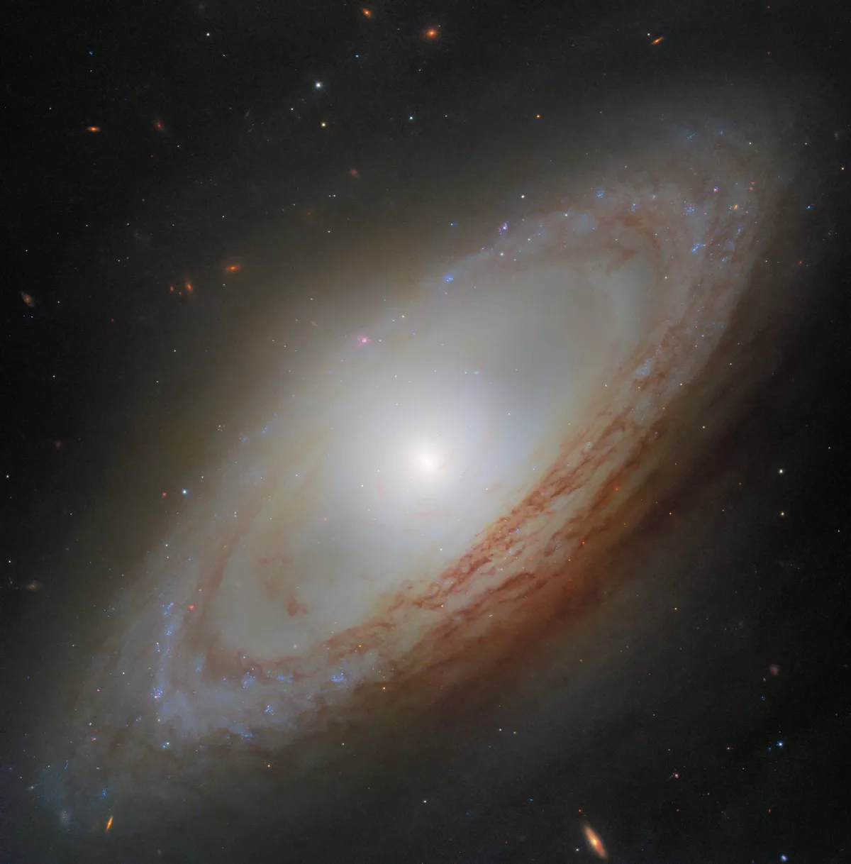 Imagem do telescópio Hubble mostrando a galáxia NGC 4698 com braços espirais e núcleo alongado.